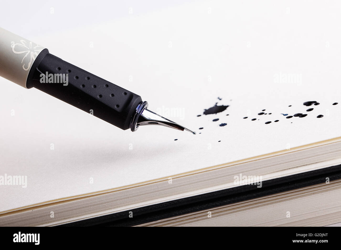Two messy black ink splats with fountain pen opened to show the nib on white paper Stock Photo