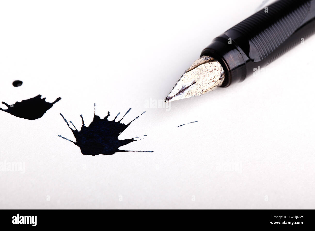 Two messy black ink splats with fountain pen opened to show the nib on white paper Stock Photo