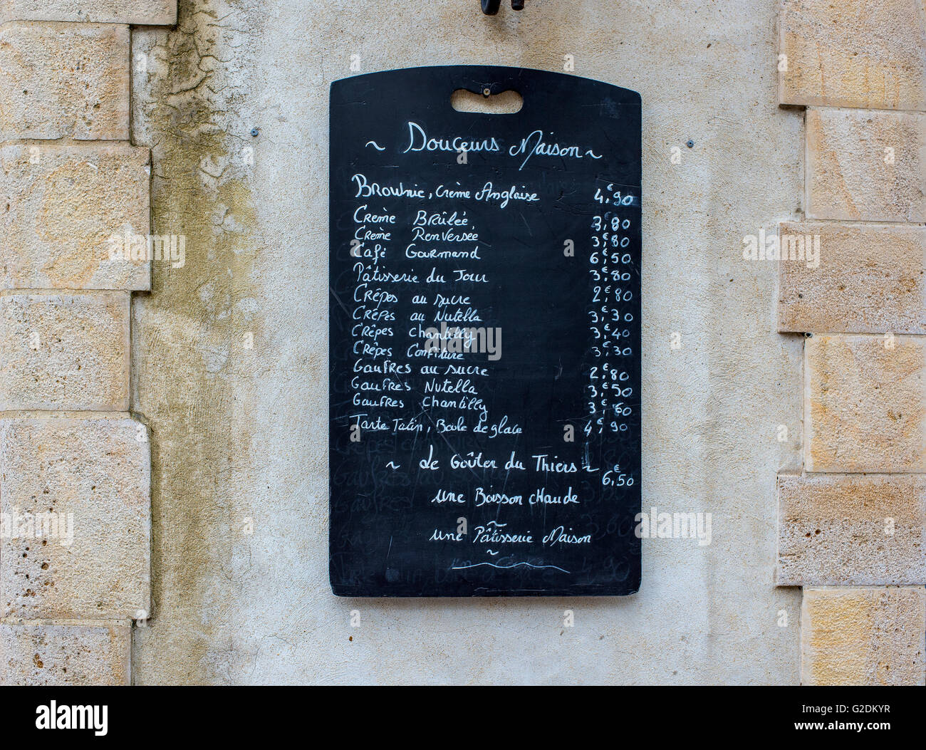 Creperie menu blackboard on a stone wall in a street of Saint-Jean de Luz. Aquitaine, France. Stock Photo
