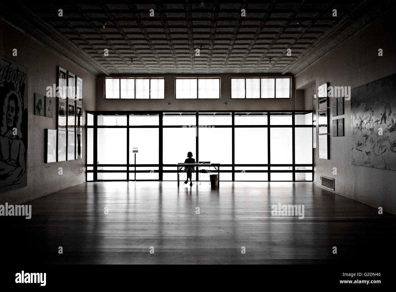 Silhouette of Woman Sitting at Desk in Art Gallery Stock Photo