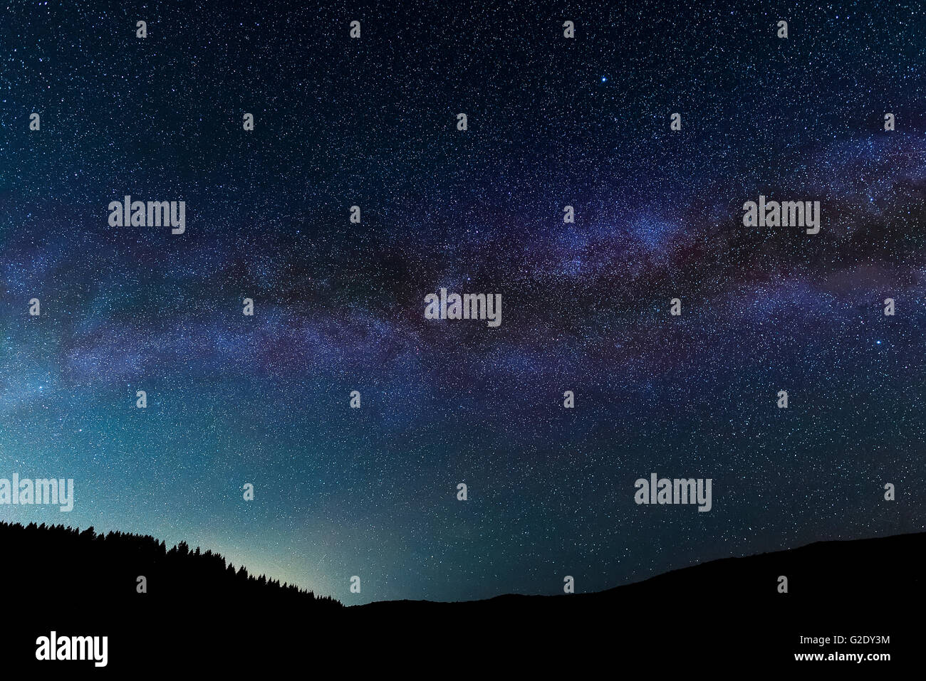 Night sky, including a section of the Milky Way, seen over a wooded hill in western Oregon. Stock Photo