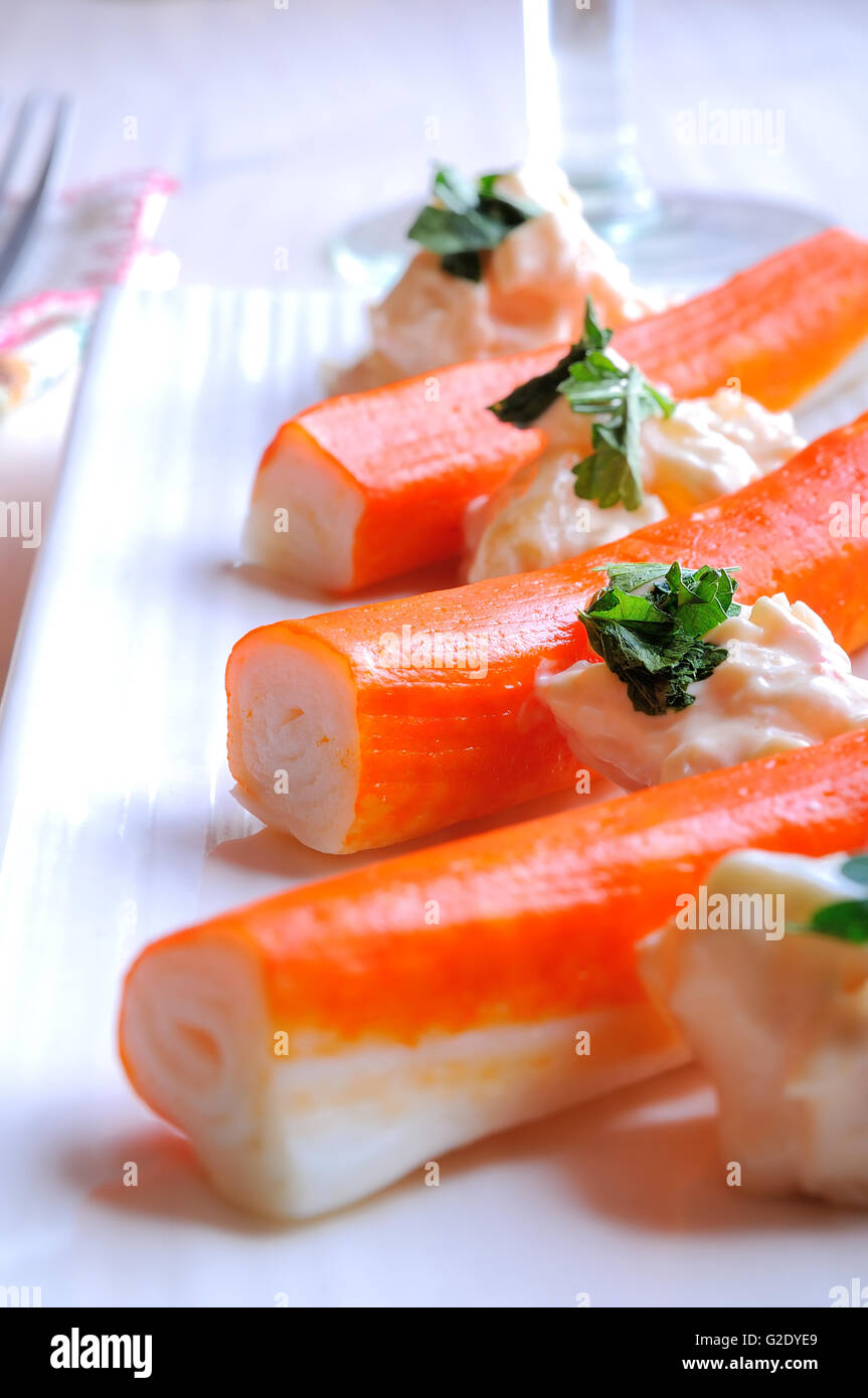 Surimi sticks with sauce on a white plate on a white wooden table closeup Stock Photo