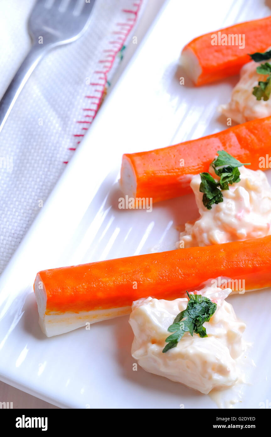 Surimi sticks with sauce on a white plate on a white wooden table top view Stock Photo