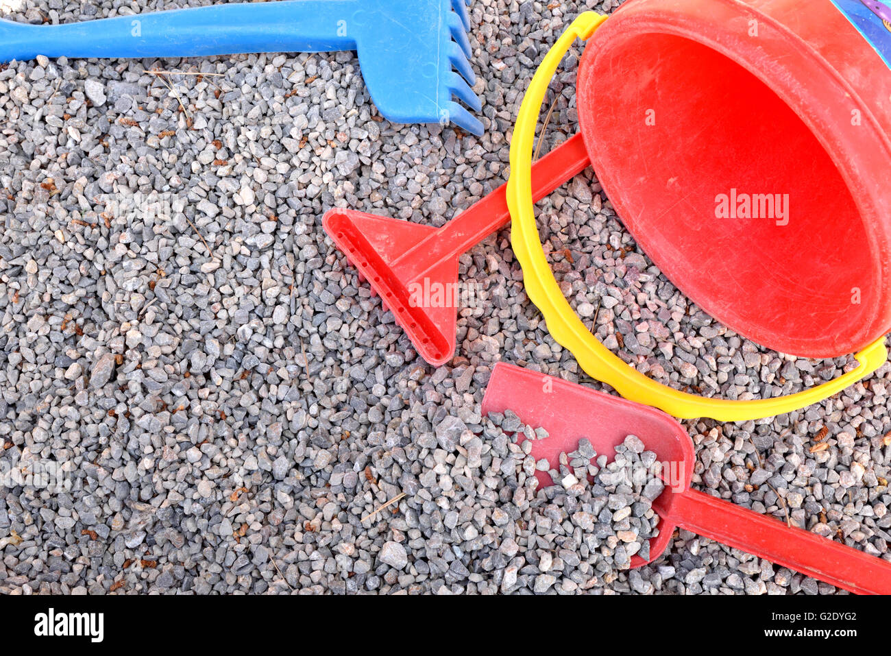 Rake, shovel and bucket child on playground gravel. Top view. Horizontal composition. Stock Photo