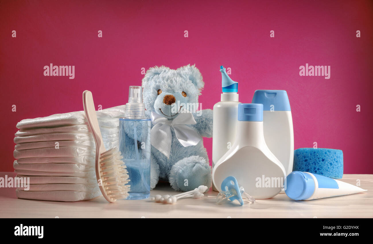 toiletries baby with diapers and pacifiers, and pink background Stock Photo
