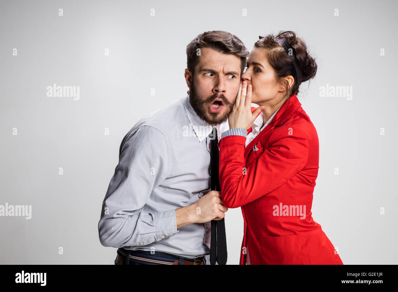 Young man telling gossips to his woman colleague at the office Stock Photo