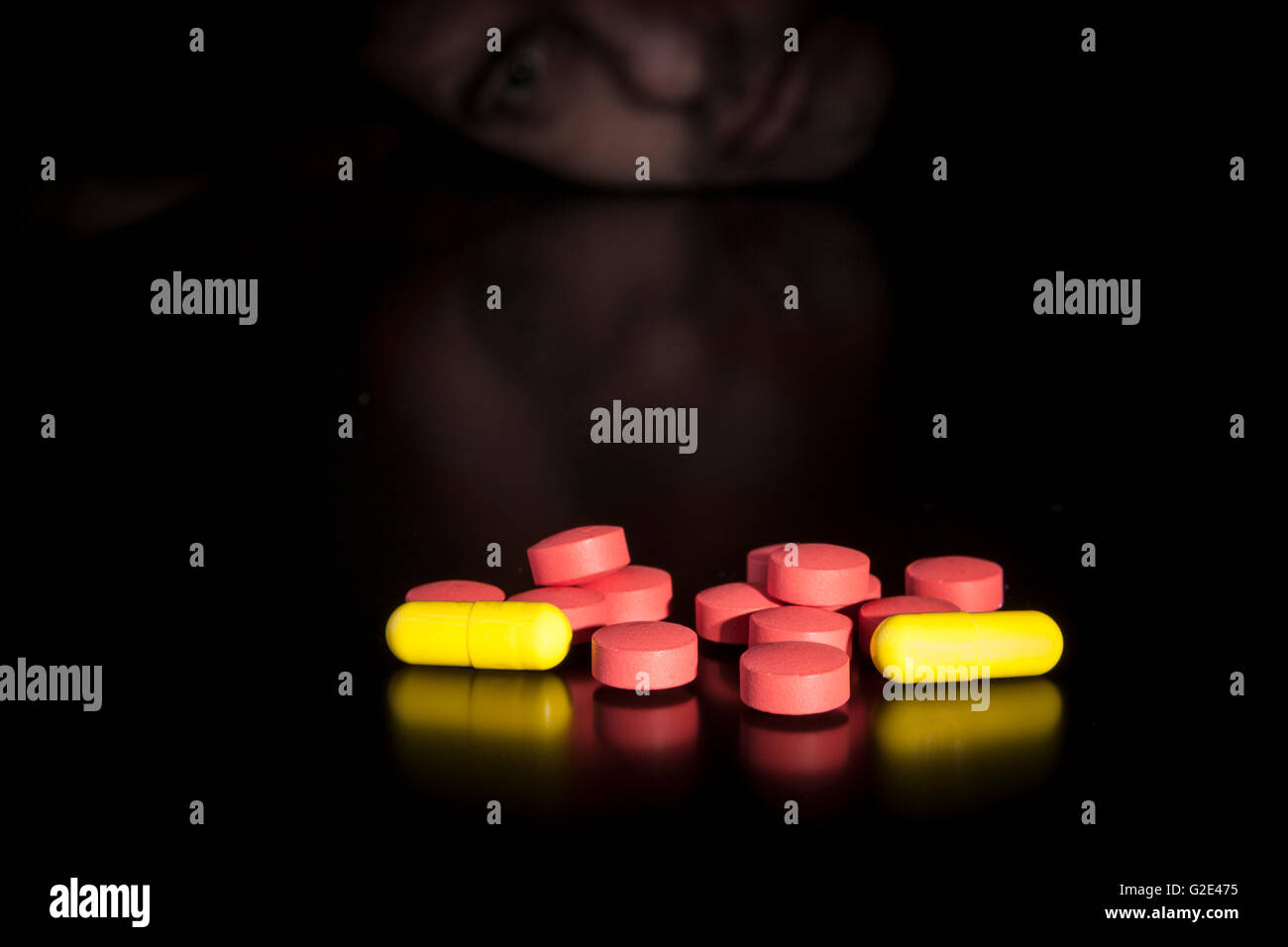 Narcotic addict with colored medicine on black table with reflection Stock Photo