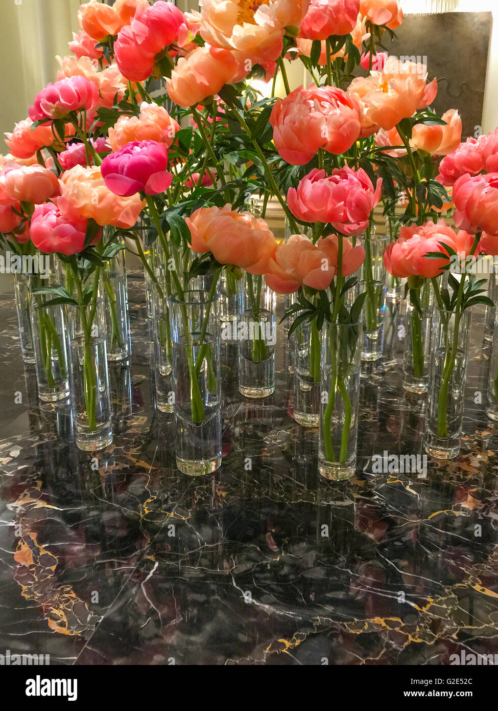 many cylinder shaped vases with one flower each on black marble table Stock Photo