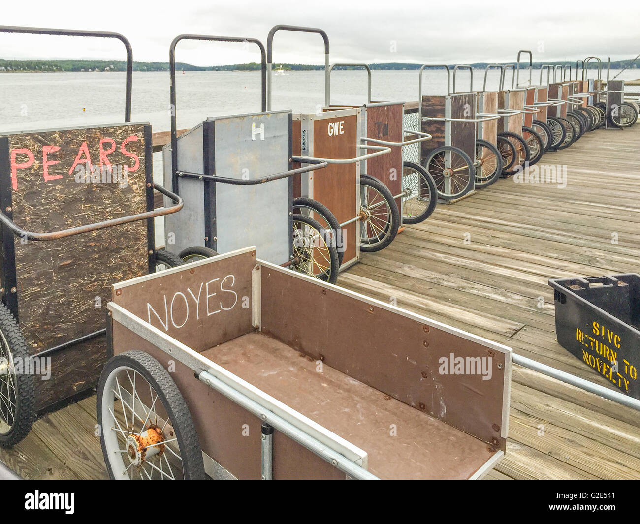 a group of empty wheeled, carts on a boat landing with the names of their owners written on each one Stock Photo