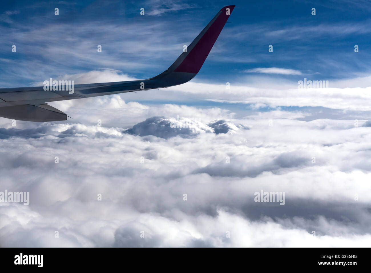 Airplane wing with fluffy white clouds adn blue sky in the background ...