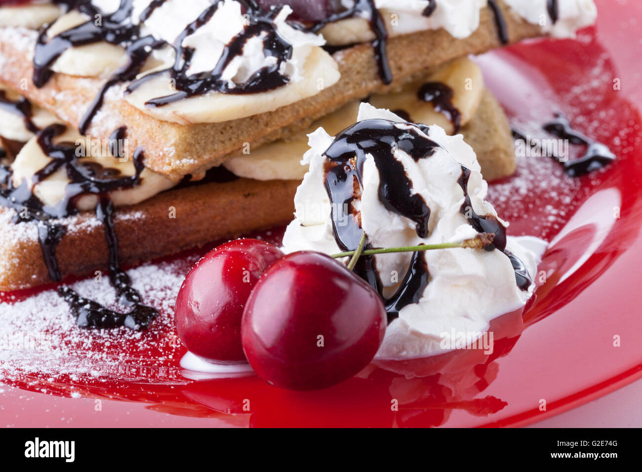 Belgian waffle with chocolate syrup whipped cream and red cherry on red ...