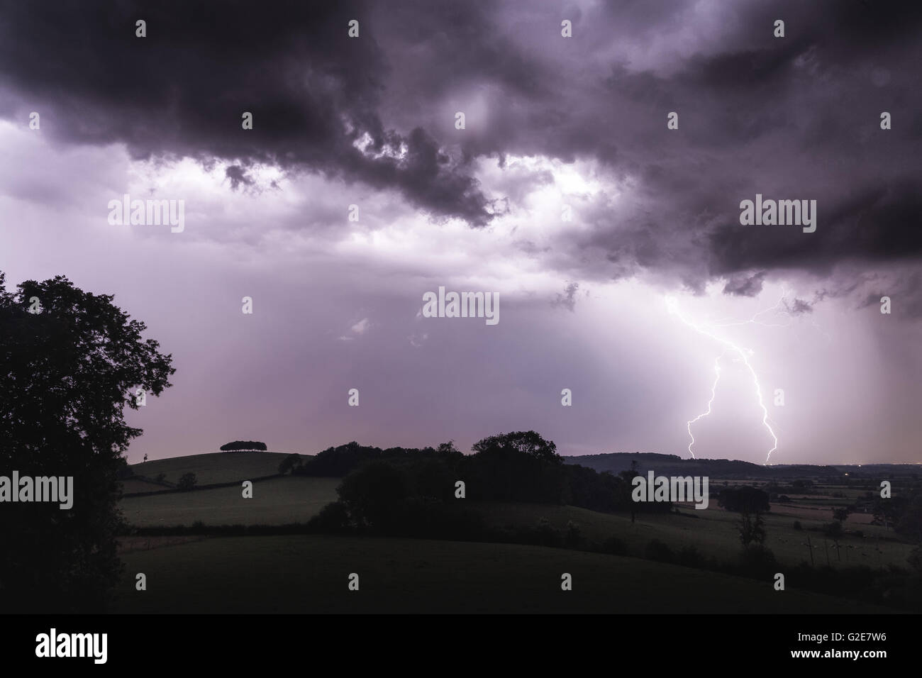 Purple Lightning Over Rural Countryside at Dusk Stock Photo