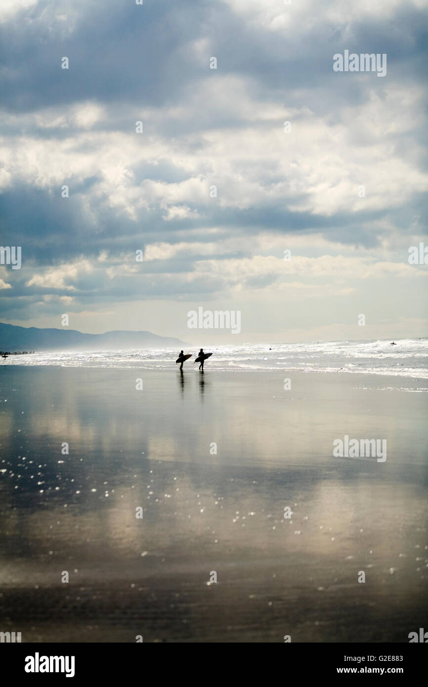 Two Surfers Walking on Beach Stock Photo