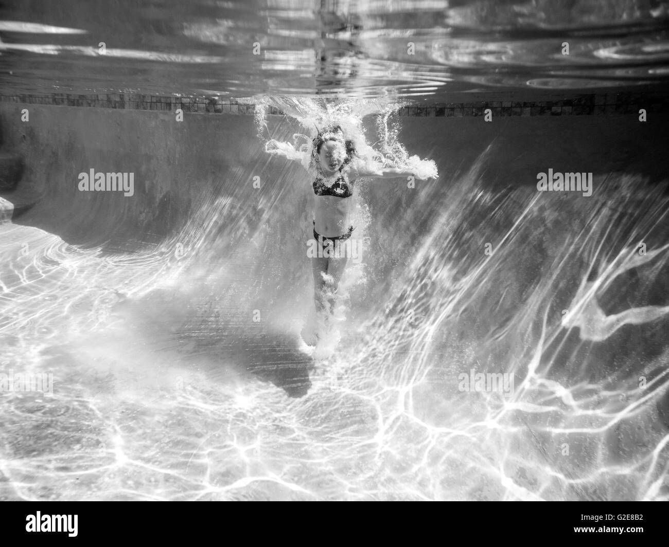 Girl Underwater after Jumping in Pool Stock Photo