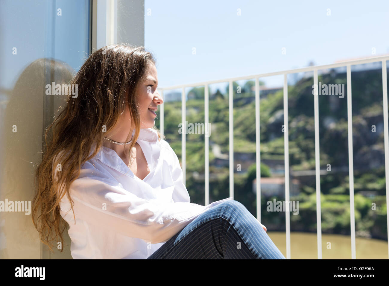 Happy young woman catching some sun at the balcony Stock Photo