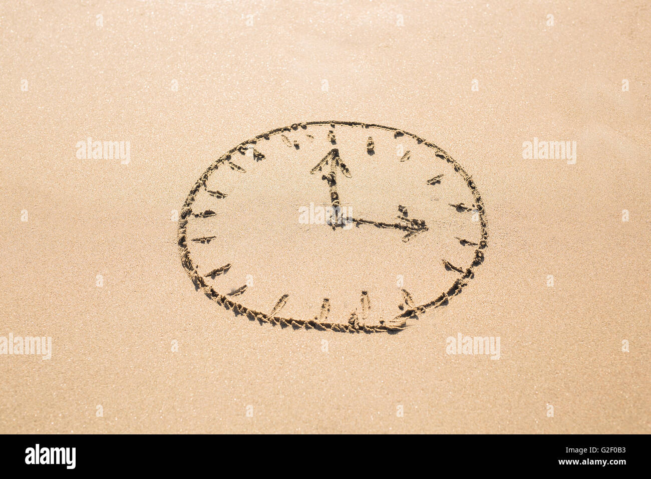 Time concept - Picture of a clock face on sandy beach. Stock Photo