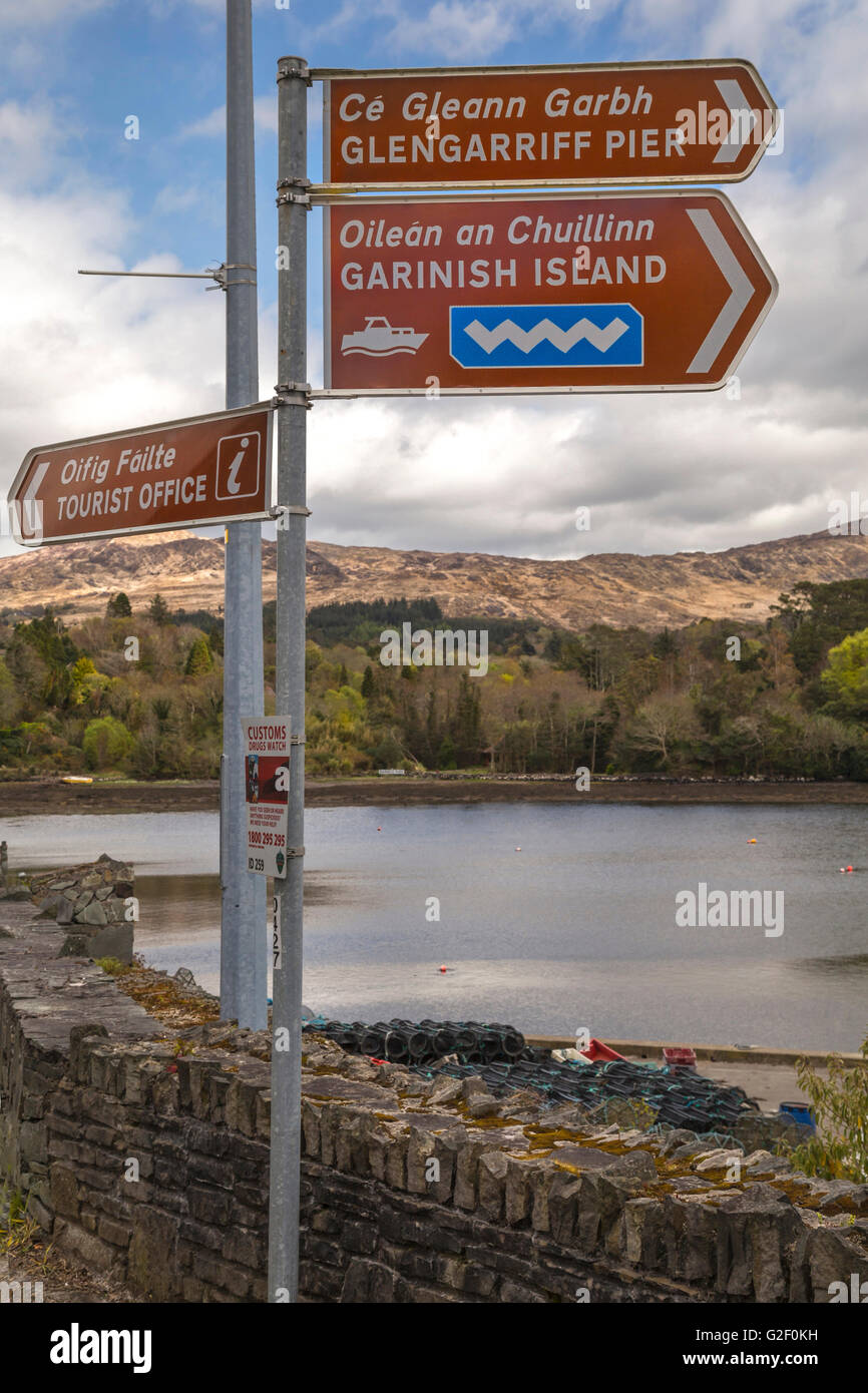 Bilingual signpost showing the way to Garnish Island Ferry, TIC, and Glengarriff Pier in English and Gaelic, Co. Cork, Ireland. Stock Photo