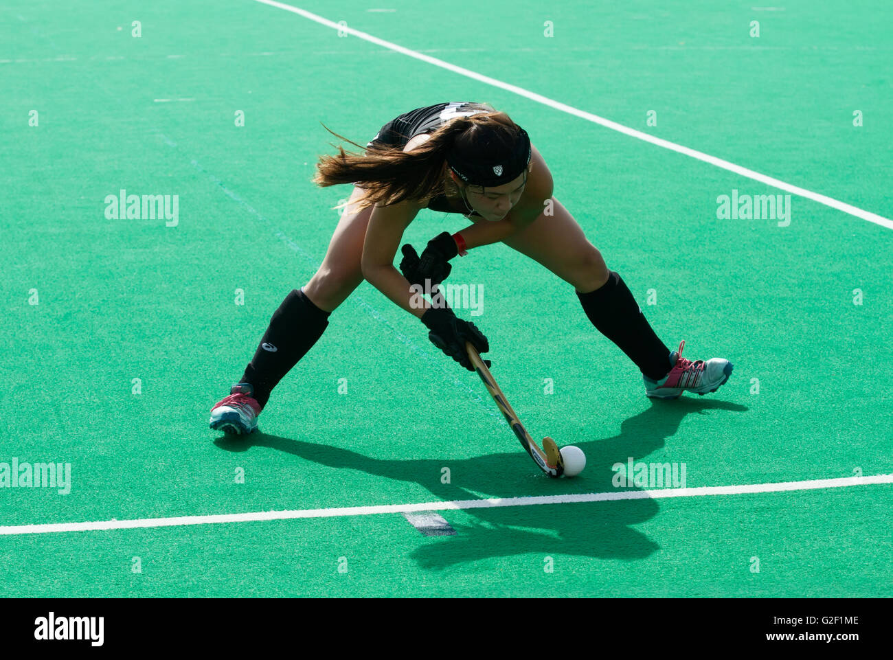 Female Field Hockey player lines up a shot Stock Photo