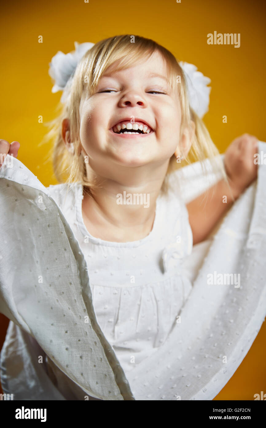 little girl with bows and fooling around in a white dress Stock Photo