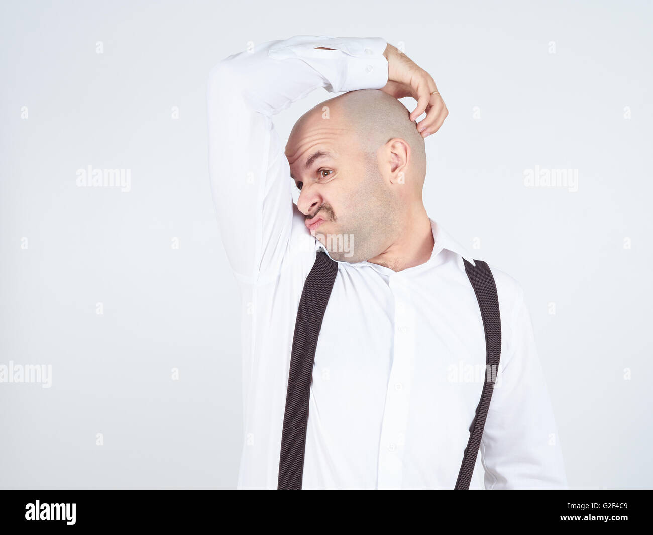 bald man, smelling sniffing his armpit, something stinks bad, foul odor isolated on background. Stock Photo