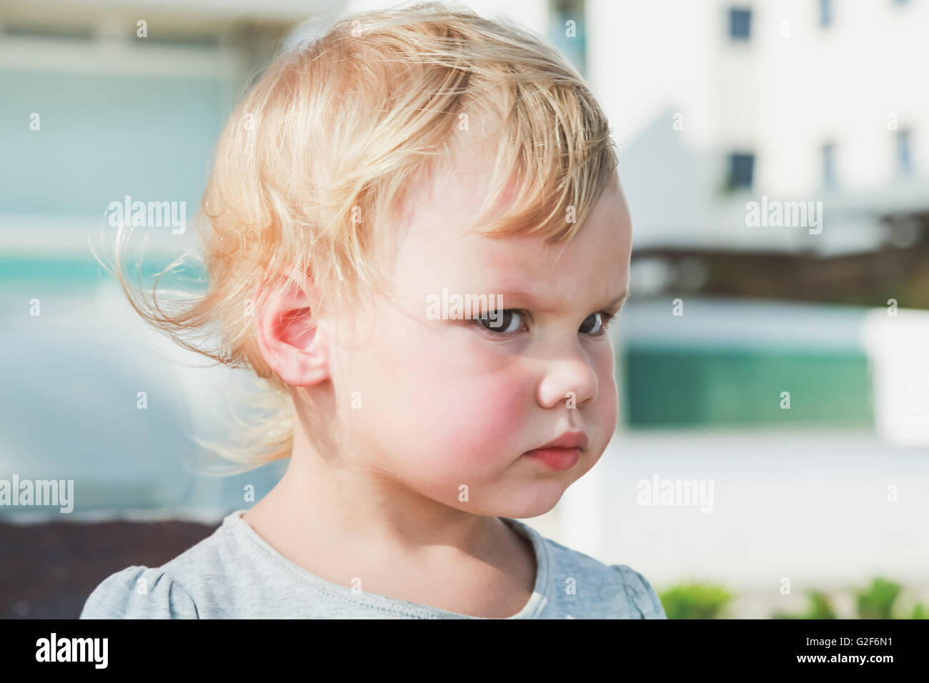 Outdoor closeup portrait of serious cute Caucasian blond baby girl Stock Photo