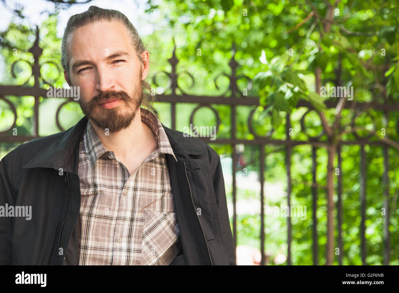 Outdoor portrait of young bearded Asian man in summer park Stock Photo