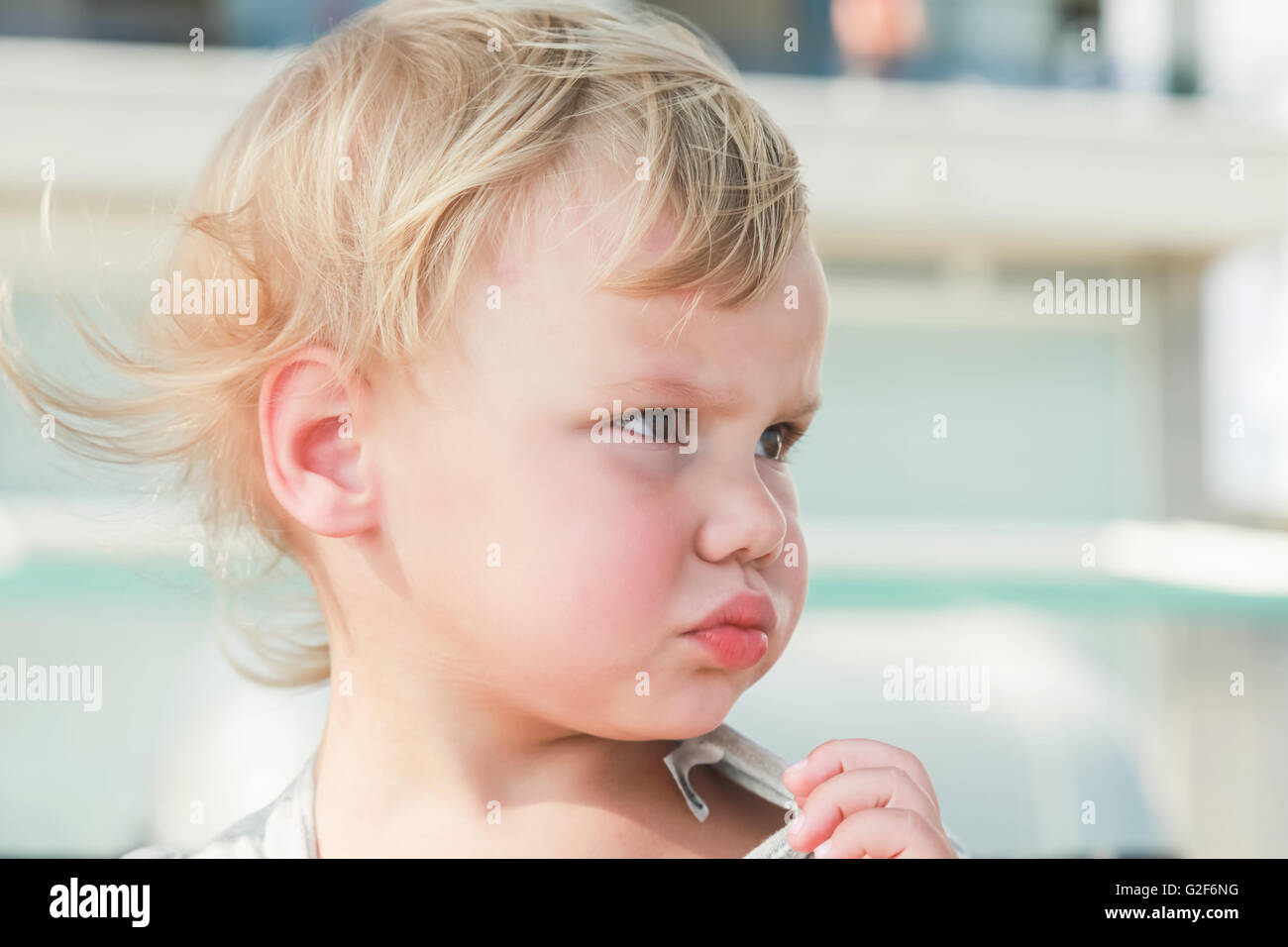 Outdoor close-up portrait of confused cute Caucasian blond baby girl Stock Photo