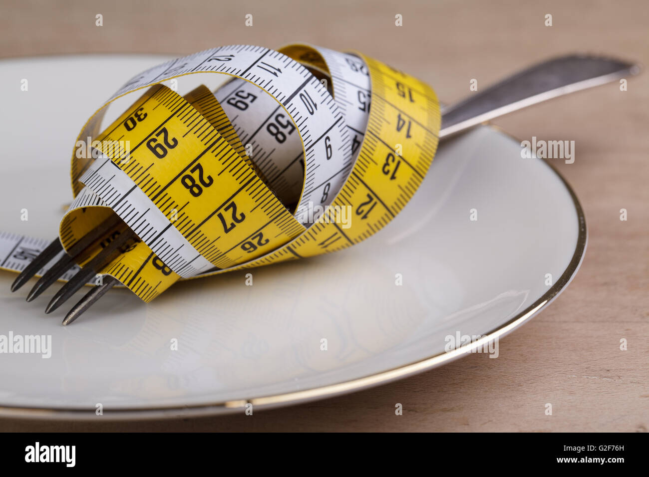Fork with measuring tape as a symbol of disciplined dieting and weight reduction Stock Photo