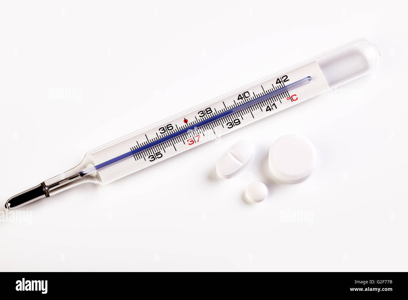 Fever thermometer showing a temperature of 39 degrees celsius and some pills Stock Photo