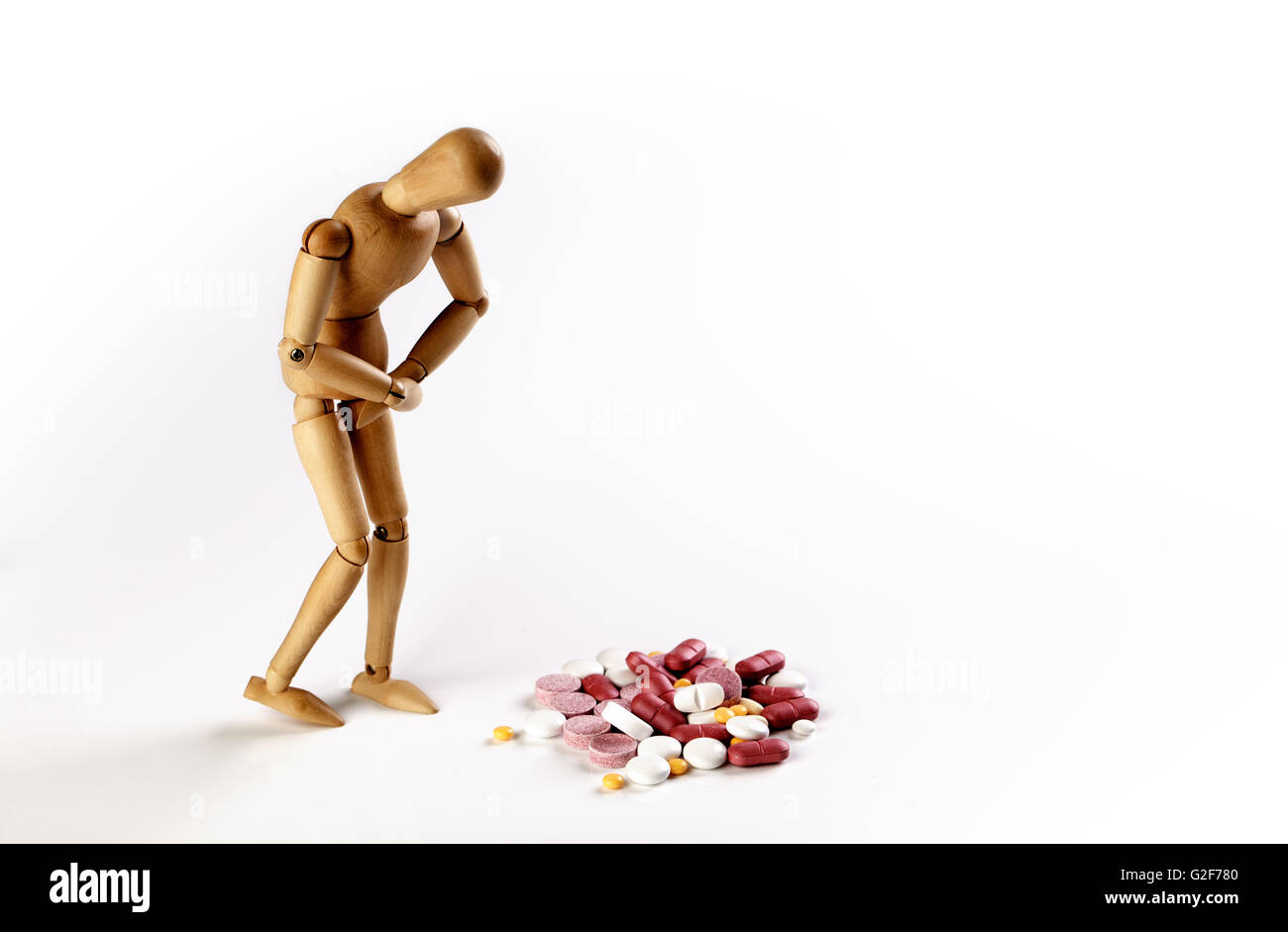Sick puppet with stomach cramps and pile of colorful pills Stock Photo