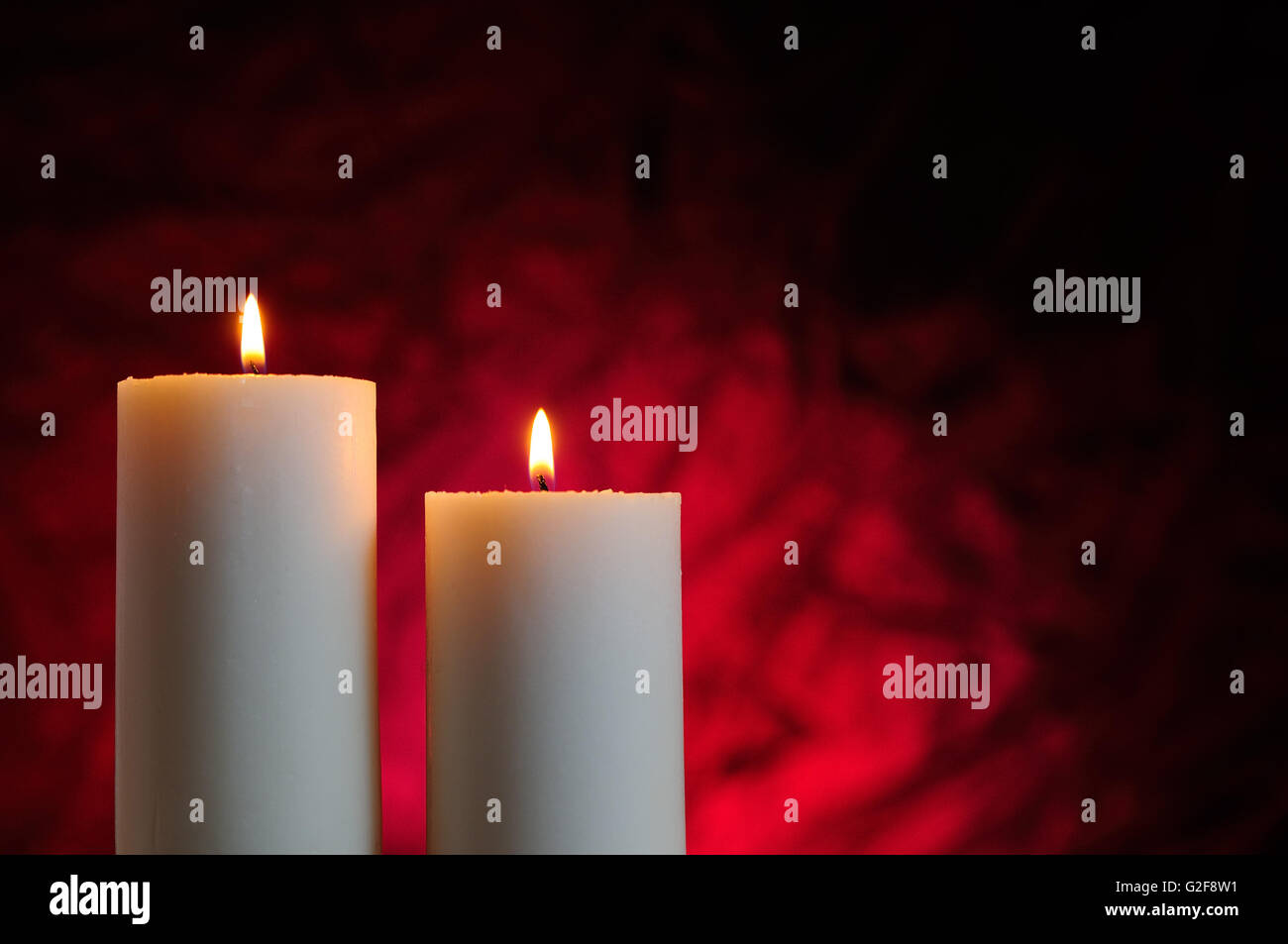 two candles lit with red background Stock Photo Alamy