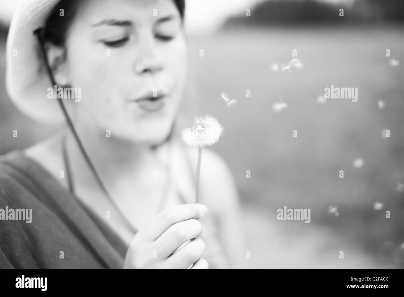 Teenage Girl Blowing on Dandelion Stock Photo