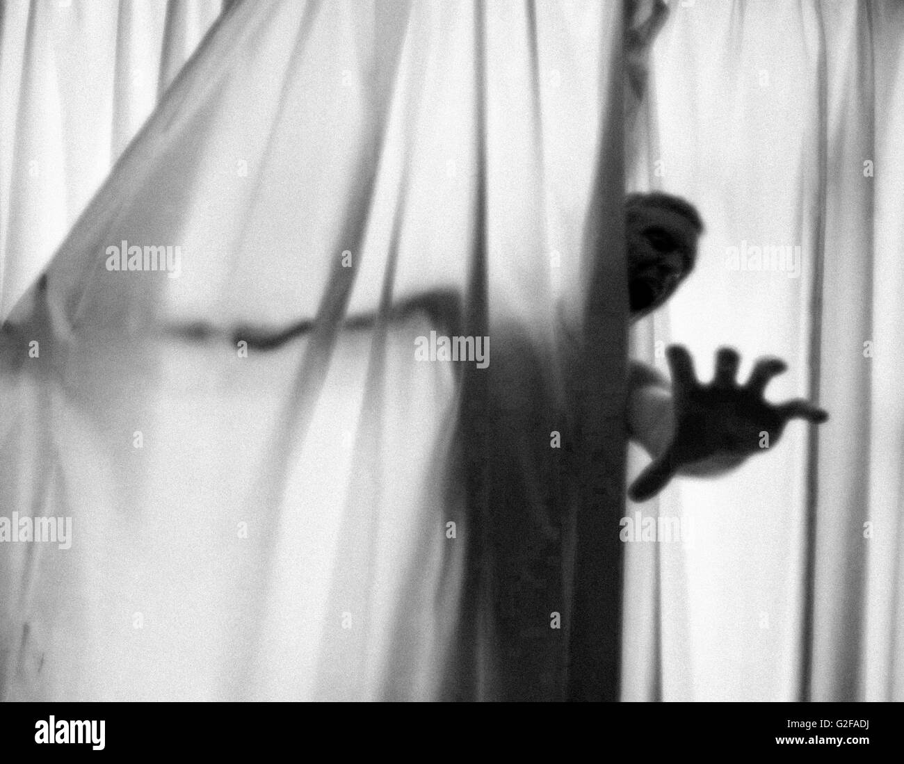 Screaming Man's Hand Reaching  out from Curtains Stock Photo
