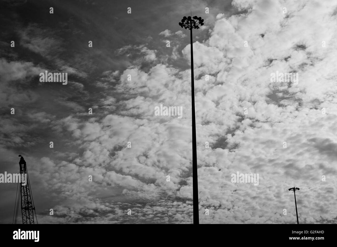 Crane and Two Industrial Light Posts Against Dramatic Sky, Low Angle