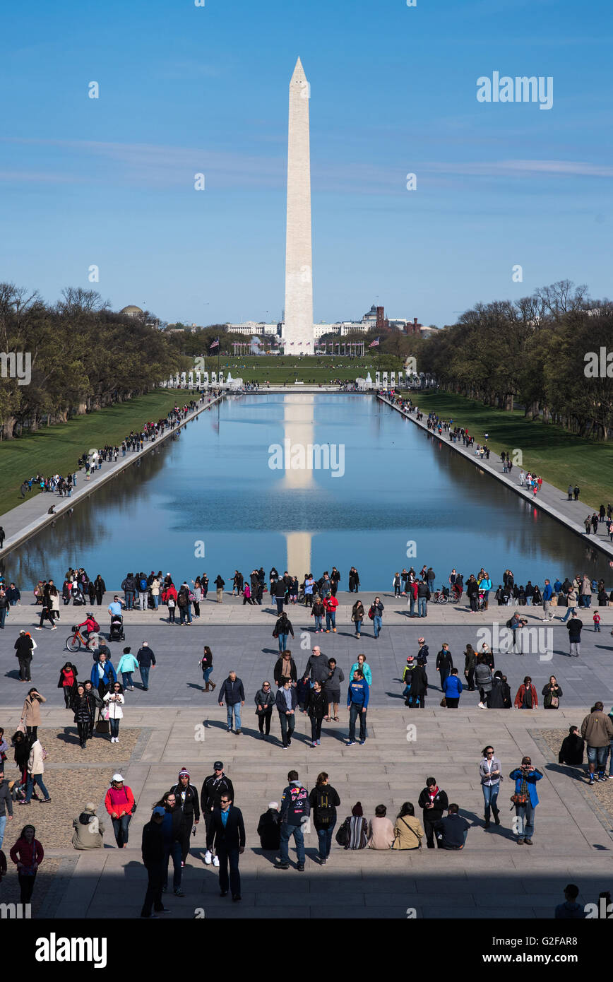 People gather at the Reflecting Pool at the National Mall with the Washington Monument seen in the distance. Stock Photo
