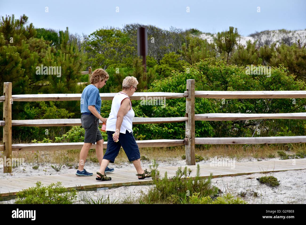 Two older woman walking down a path to the beach Stock Photo