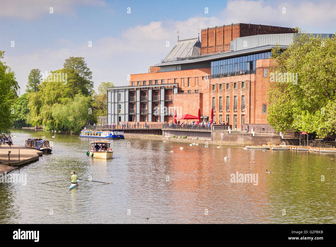 Royal Shakespeare Theatre and the River Avon and  people in boats on the river on a sunny weekend in late spring, Stratford-upon Stock Photo