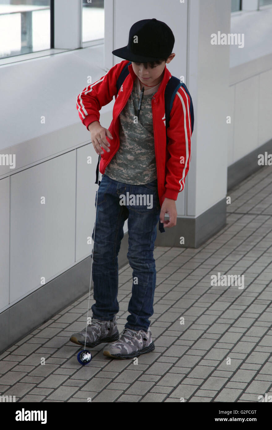 Young boy is playing yoyo at the platform of the station or in the