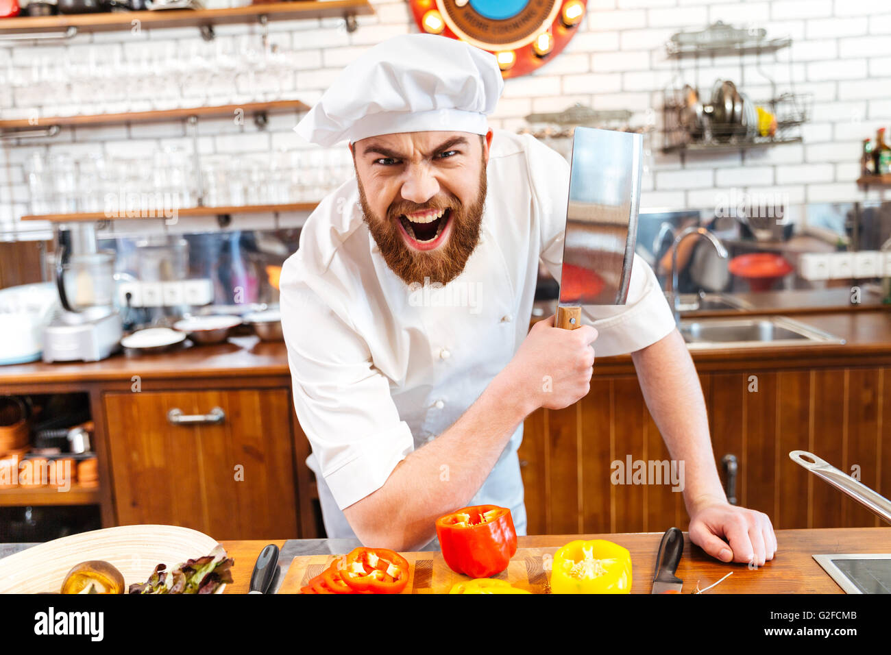 Angry bearded chef cook holding meat cleaver knife and shouting on the