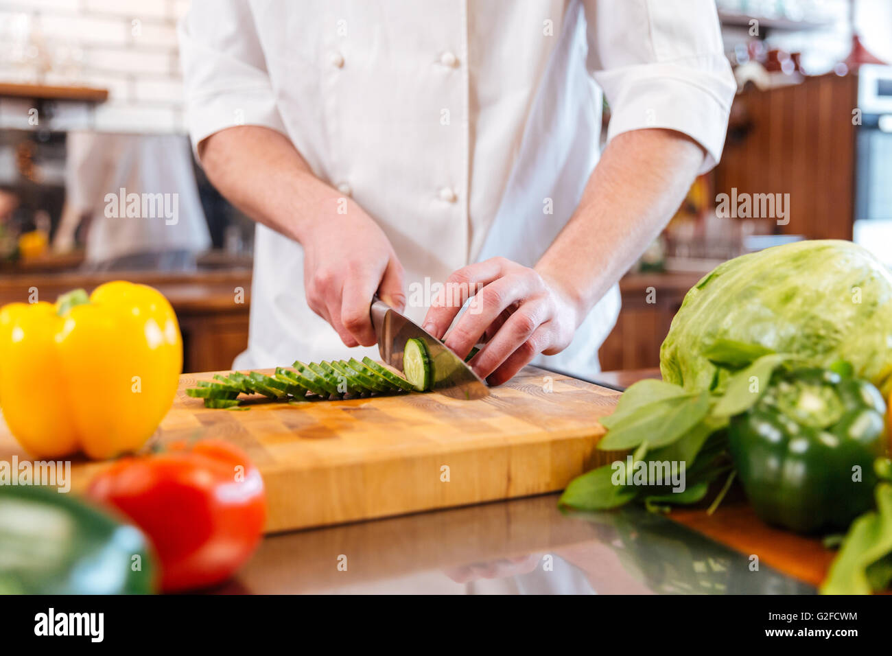 Closeup of hands of chef cook cutting fresh vegetables and making vegetarian salad on the kitchen Stock Photo