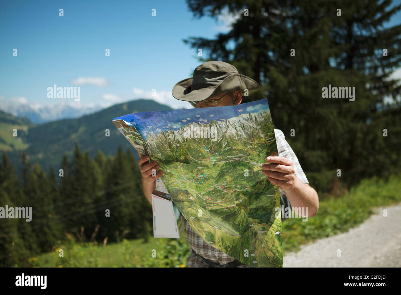 Man in Hiking gear studying a map looking for the direction while hiking in the european alps Stock Photo