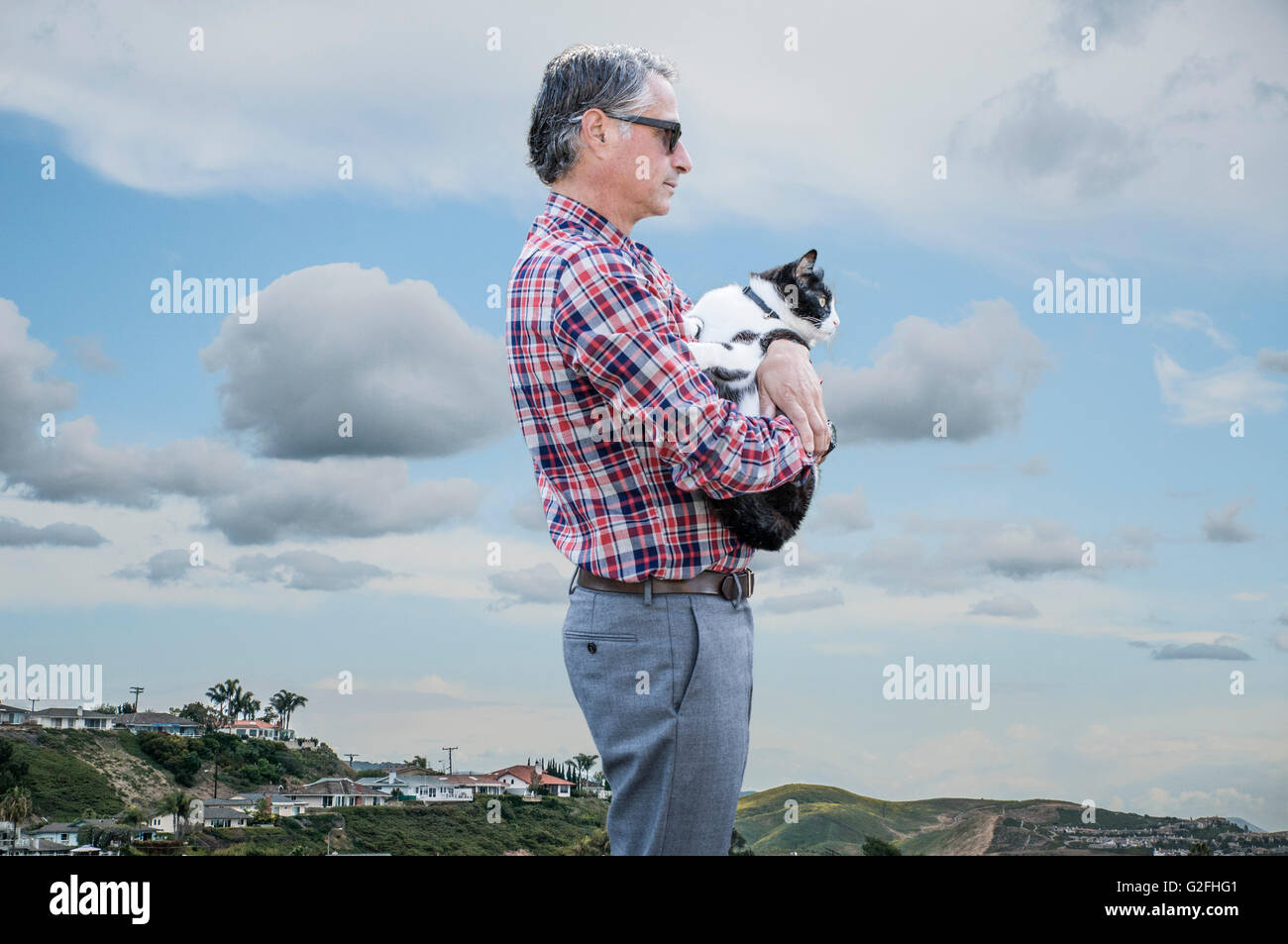 Profile of Man in Sunglasses and Plaid Shirt Holding Cat Stock Photo