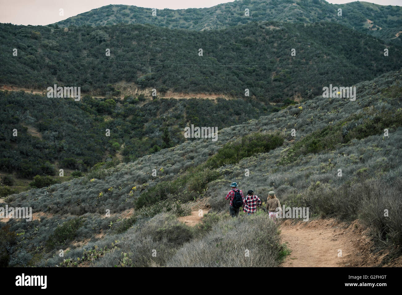 Father and Two Children Hiking on Hillside Trail Stock Photo