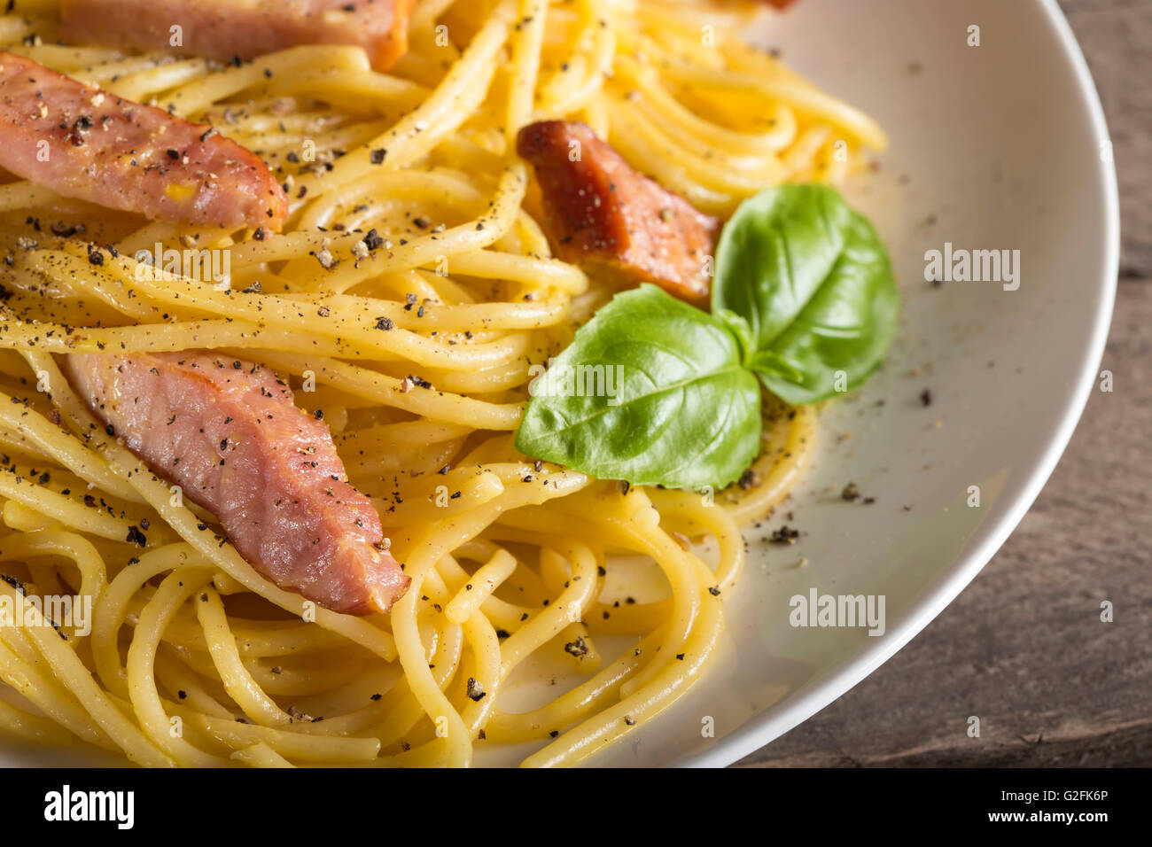 Spaghetti carbonara on white plate on rustic wooden background Stock Photo