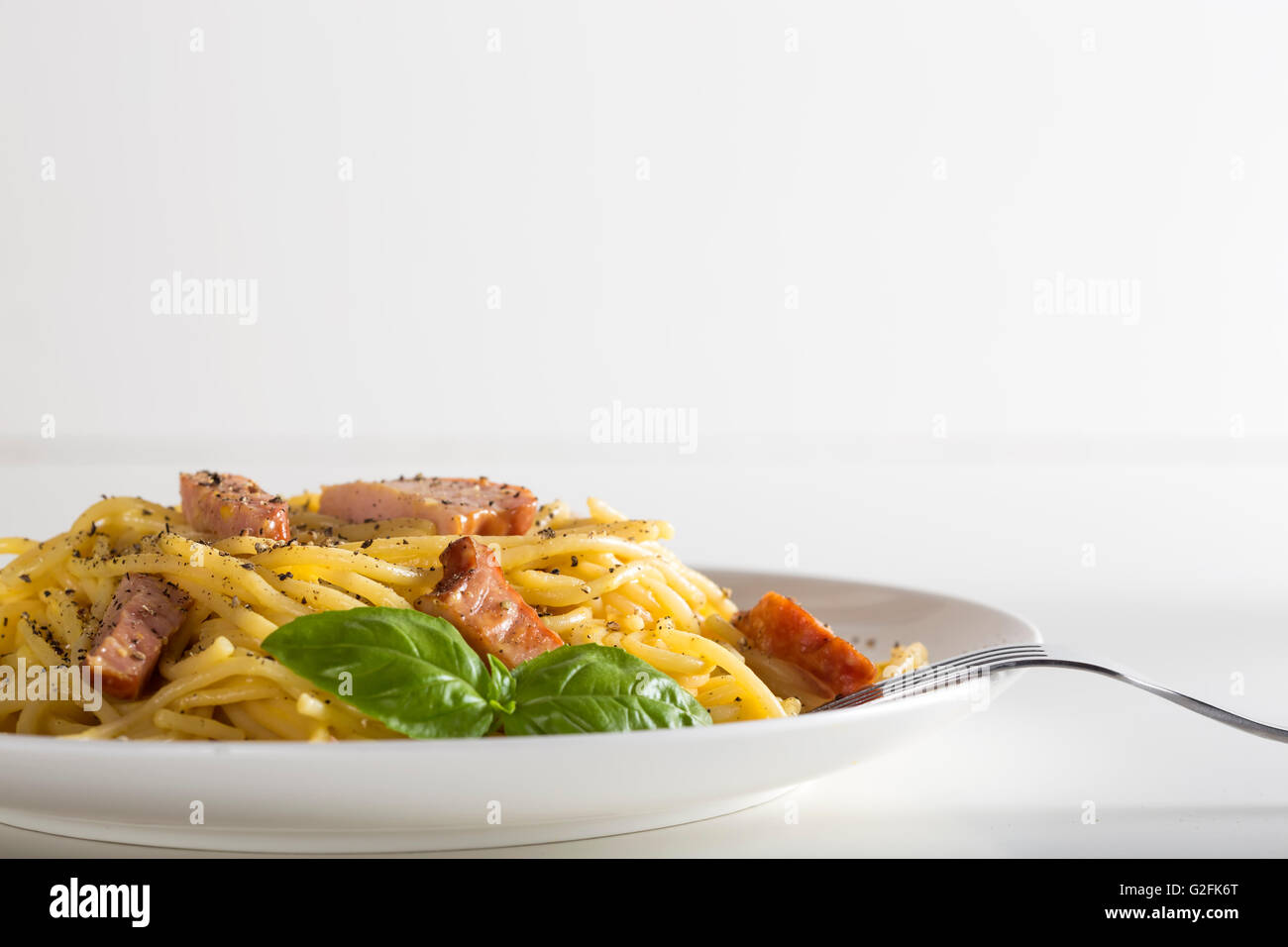 Spaghetti carbonara on white plate with fork and copy space Stock Photo
