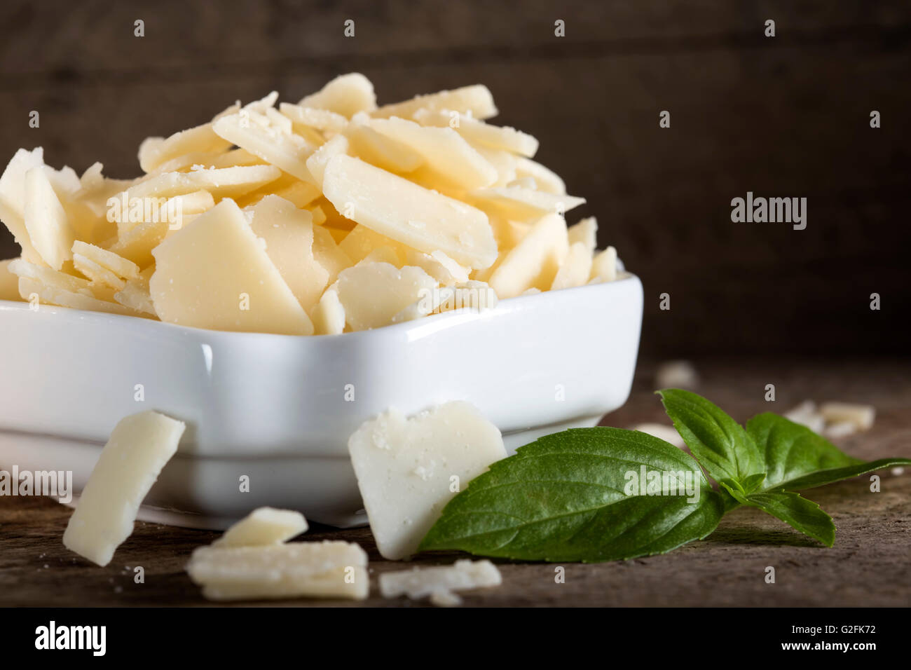 Bowl with parmesan cheese flakes on rustic table Stock Photo