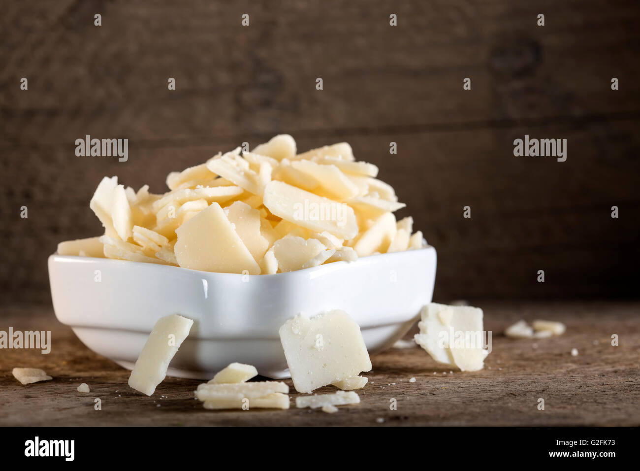 Bowl with parmesan cheese flakes on rustic table Stock Photo