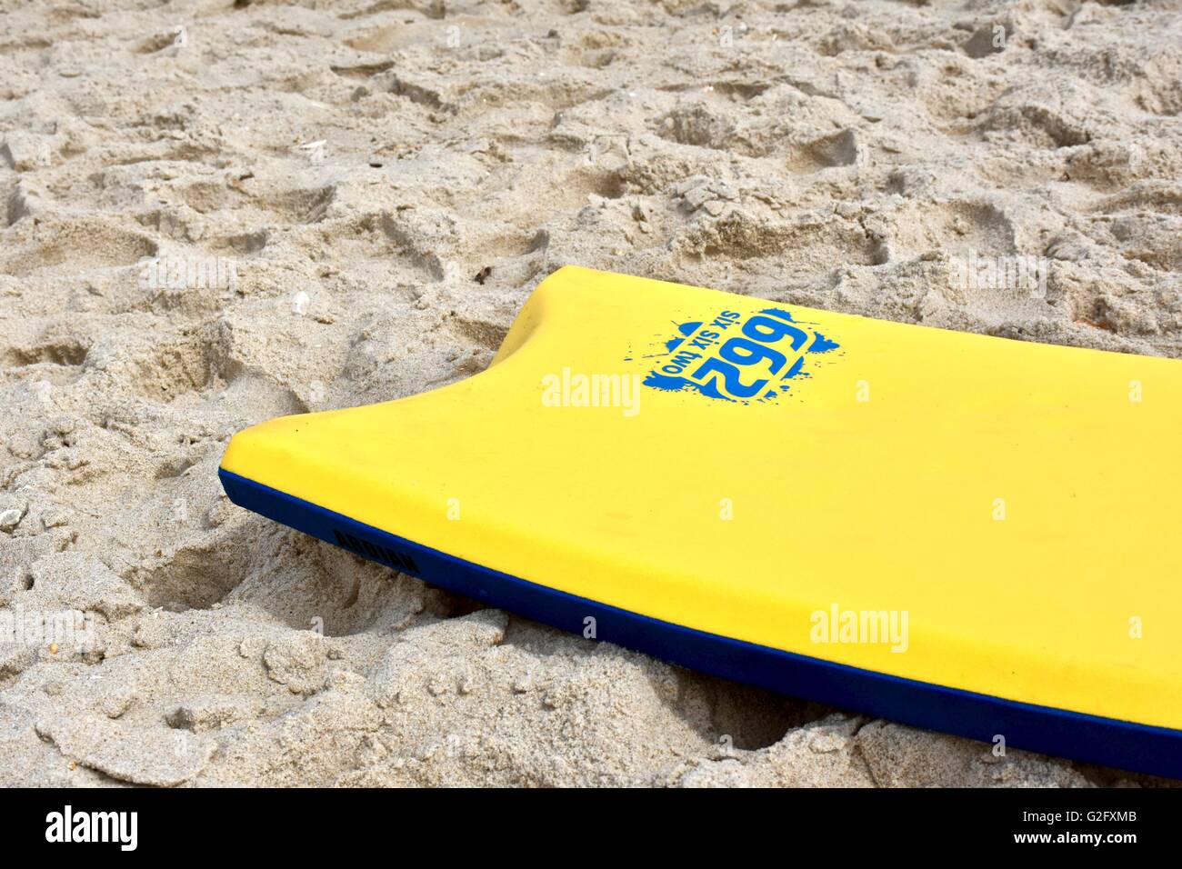 A yellow boogie board laying in the sand on the beach Stock Photo Alamy
