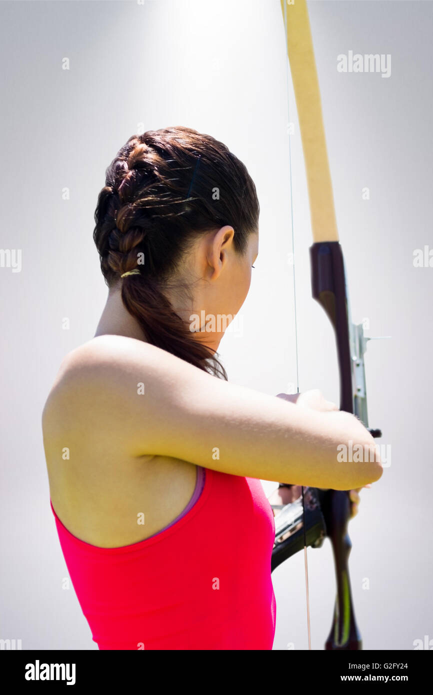 Composite image of rear view of sportswoman doing archery on a white background Stock Photo