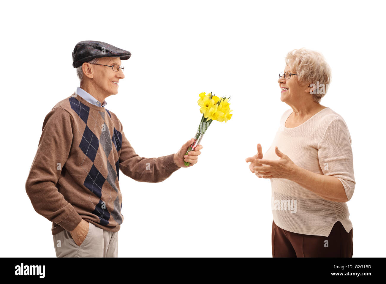 Thoughtful senior man giving flowers to a joyful senior lady isolated on white background Stock Photo
